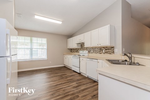 a kitchen with white cabinets and a sink and a refrigerator