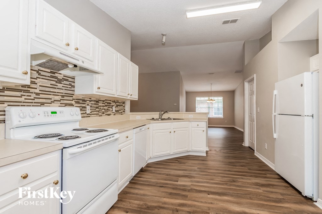 a kitchen with white cabinets and appliances and a wood floor