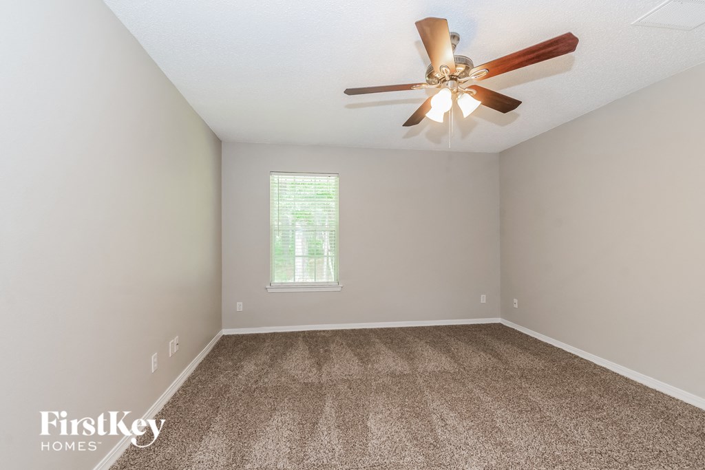 a bedroom with a ceiling fan and a carpeted floor