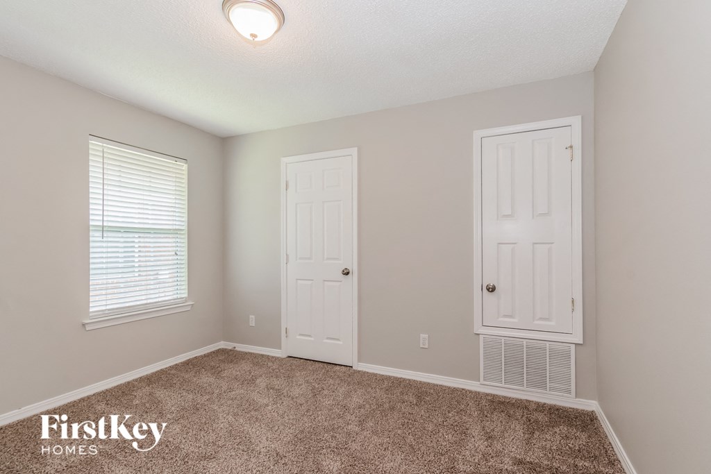 a bedroom with a carpeted floor and a door and a window