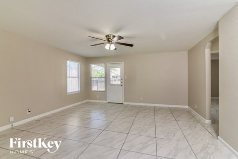 a spacious living room with tile flooring and a ceiling fan
