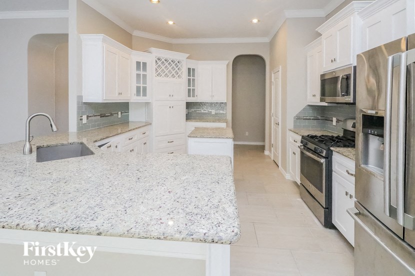 a large white kitchen with stainless steel appliances and white counter tops