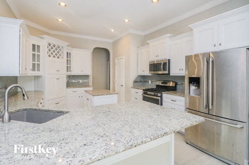a white kitchen with a marble counter top and stainless steel appliances