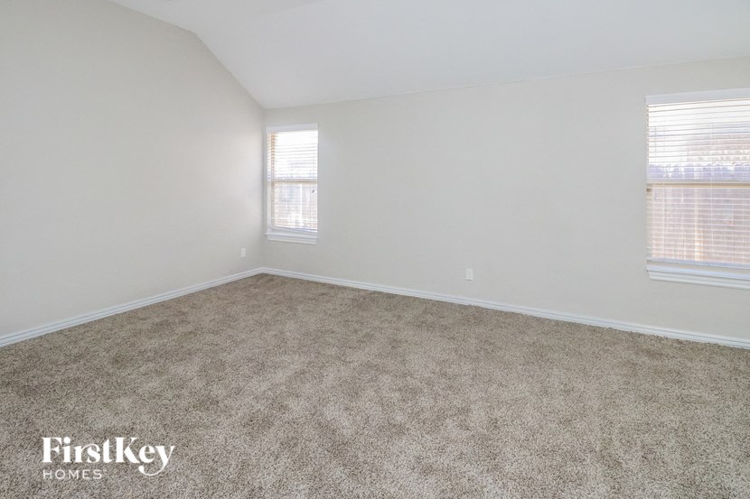 an empty living room with carpet and two windows