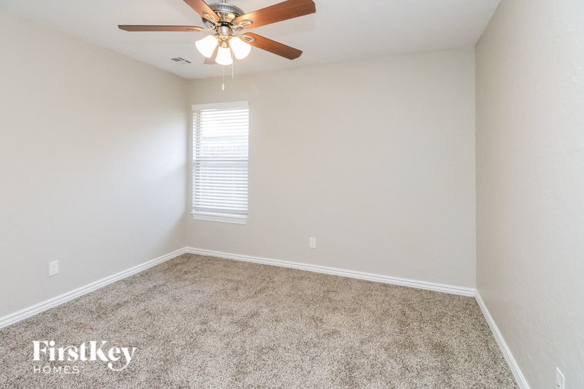 an empty room with a ceiling fan and a window