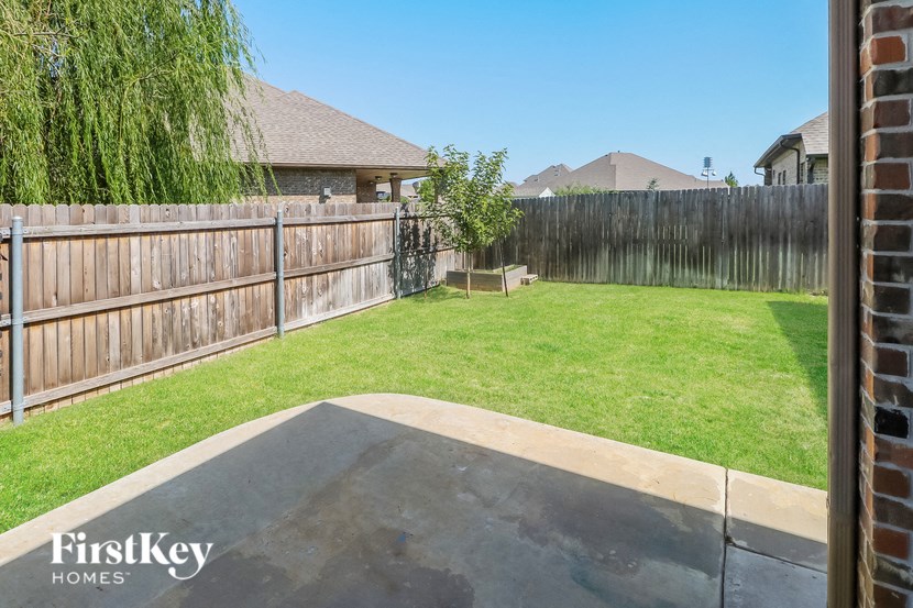 a backyard with a wooden fence and a grass lawn