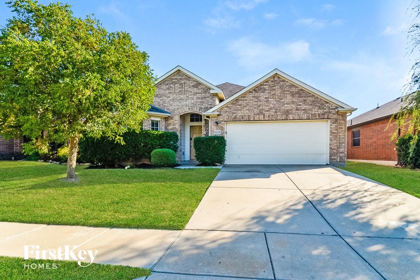 A house with a garage and a tree in front.