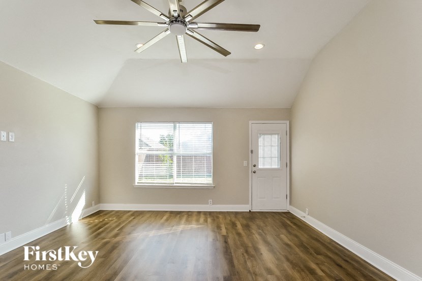 A room with a ceiling fan and wooden floors.