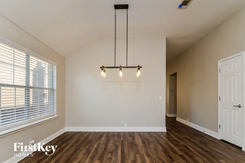 A room with a light hanging from the ceiling and a door on the right.