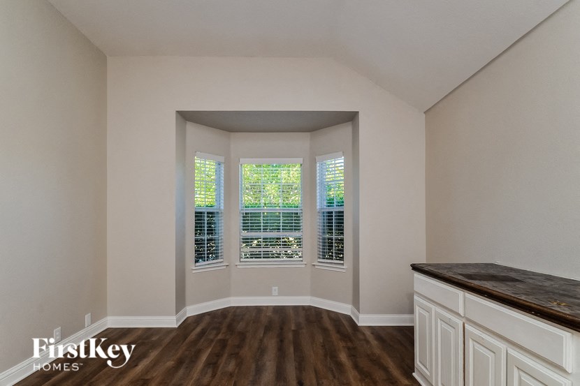 A room with a wooden floor and a window with blinds.