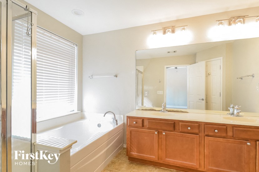 A bathroom with a tub, sink, and mirror.
