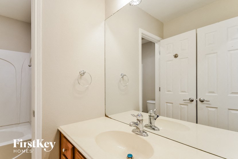 A bathroom with a sink, mirror, and two doors.