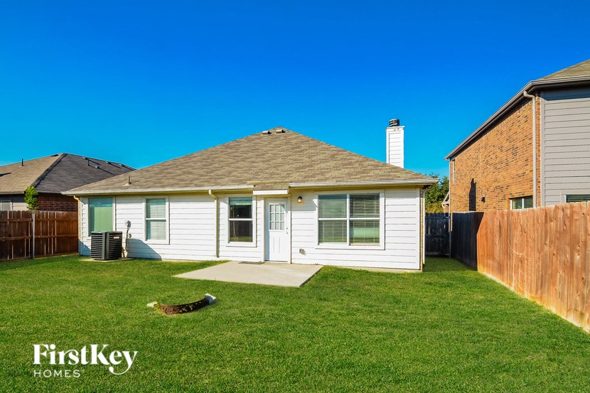 A house with a white exterior and a brown roof is shown with a blue sky in the background.
