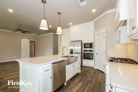 A kitchen with white cabinets and a wooden floor.