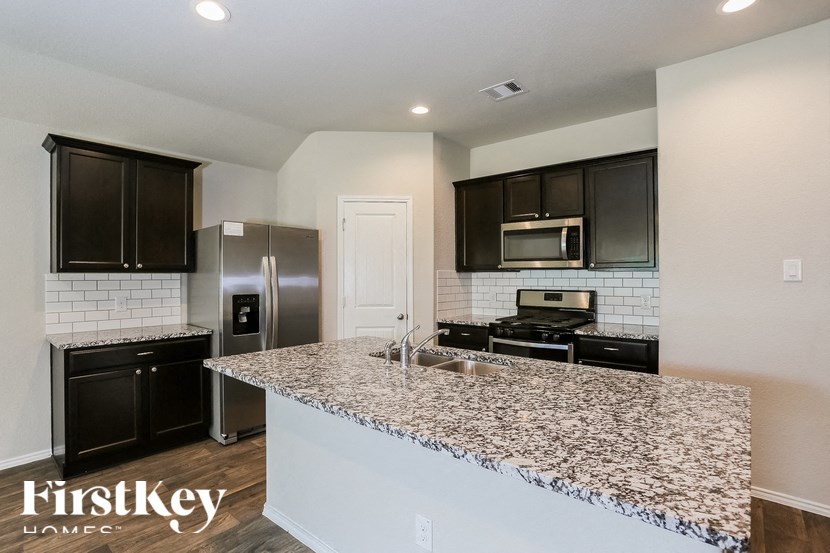 a kitchen with a granite counter top and a stainless steel refrigerator
