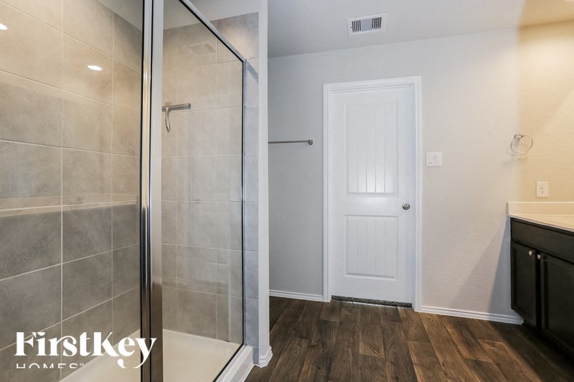 a bathroom with a shower and a sink and a white door