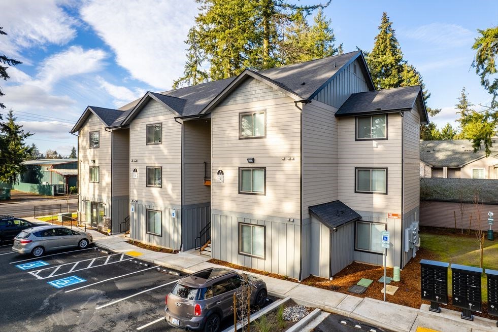 an apartment building with cars parked in a parking lot