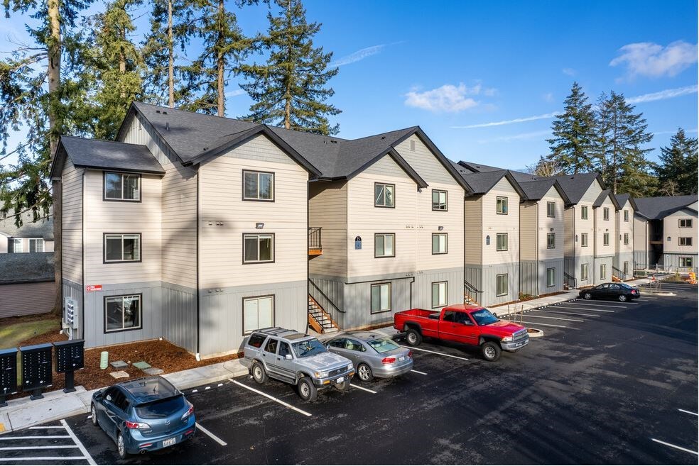 an apartment building with cars parked in a parking lot