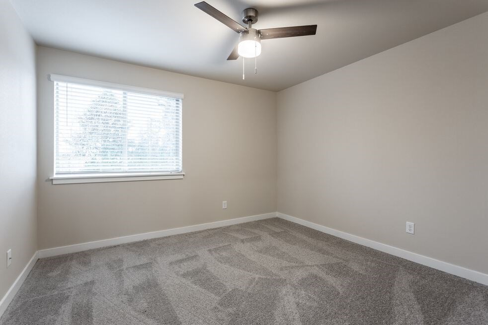 an empty room with a ceiling fan and a window