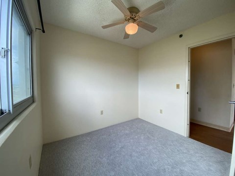 an empty living room with a ceiling fan and a window