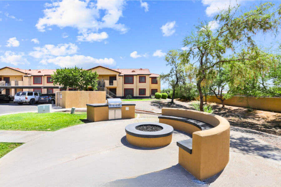 a park with benches and a fire pit in front of an apartment building