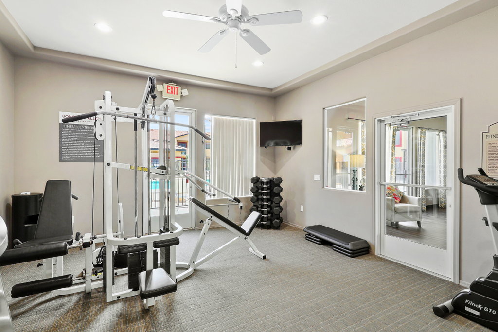 a gym with cardio equipment and a ceiling fan