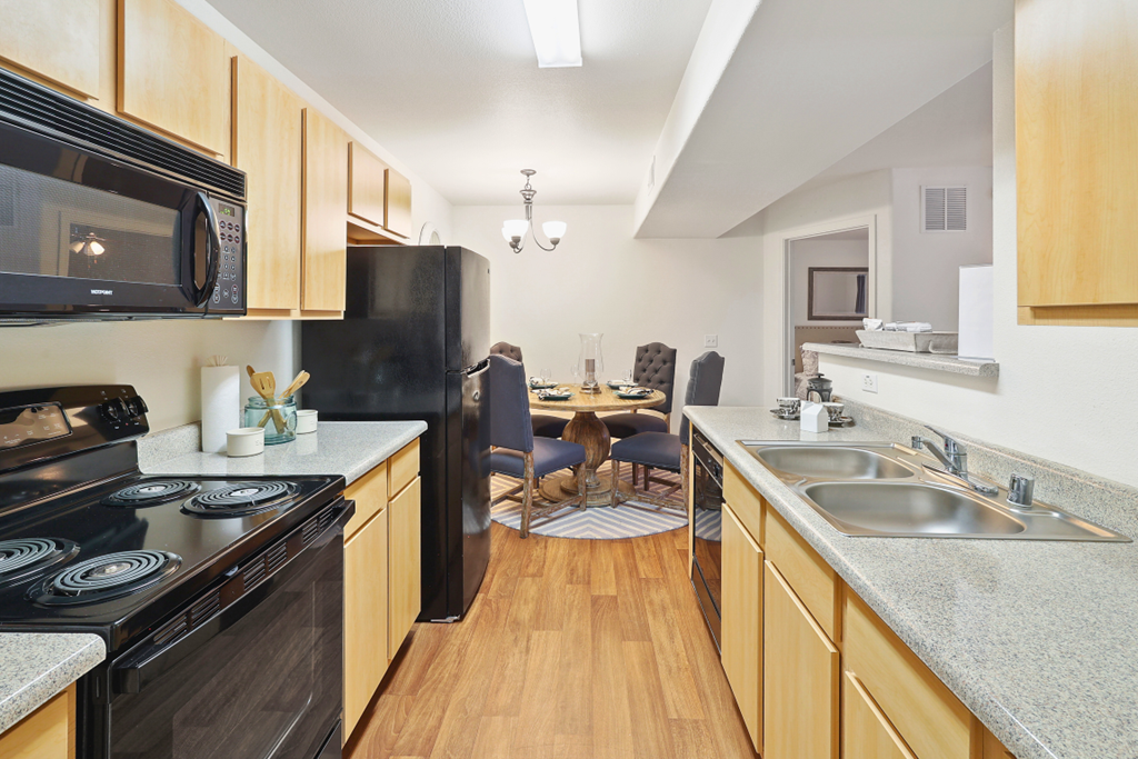 full kitchen with black appliances and a dining room with a table
