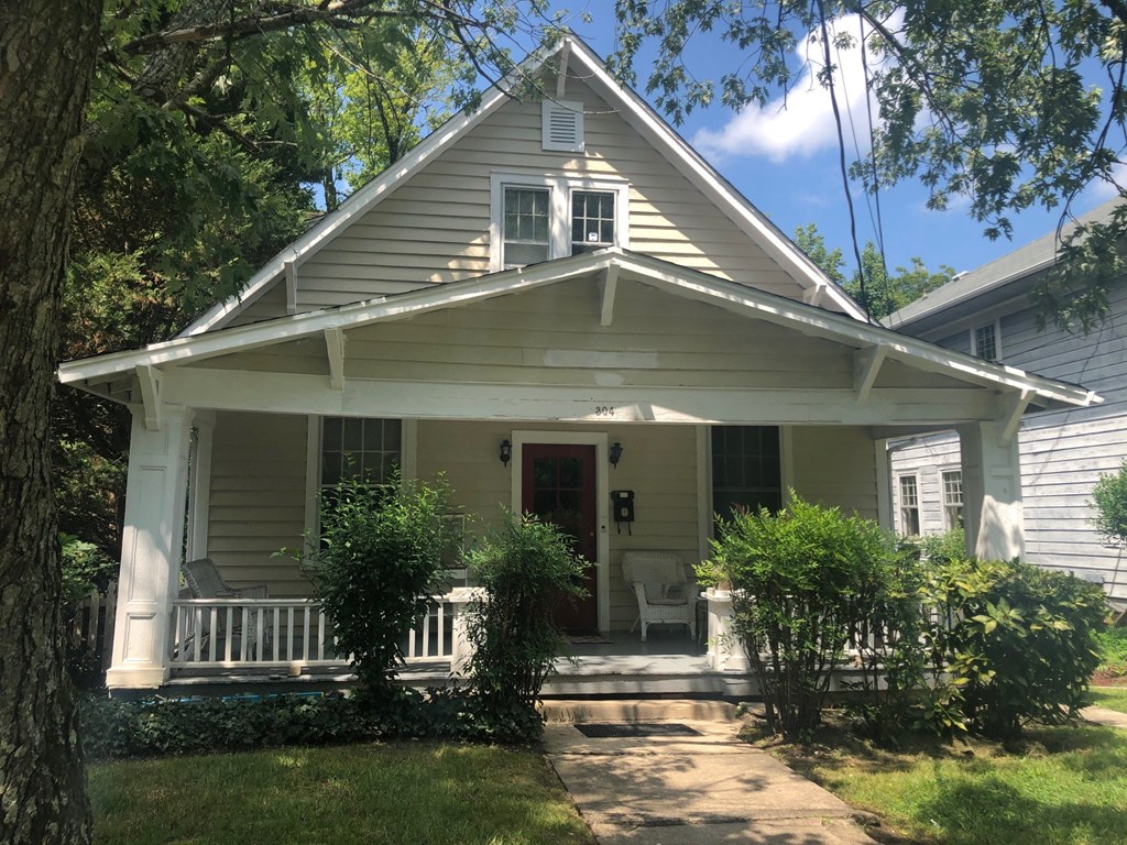 a white house with a porch with a white rocking chair on it