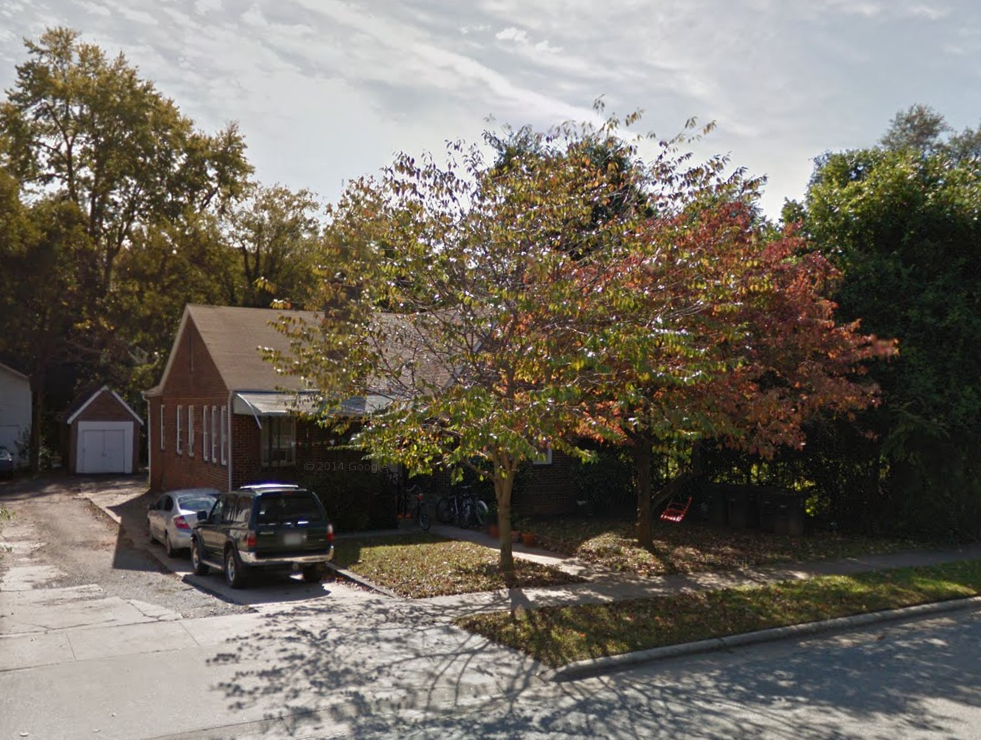 a tree in front of a house with cars parked