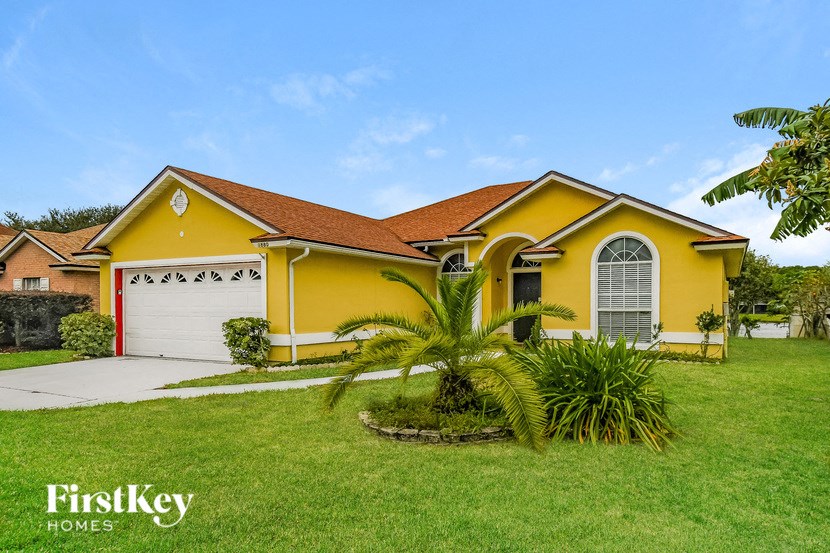 a yellow house with a garage and a palm tree in the yard