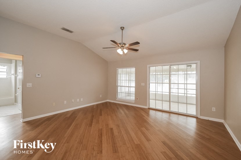 the spacious living room with hardwood flooring and a ceiling fan