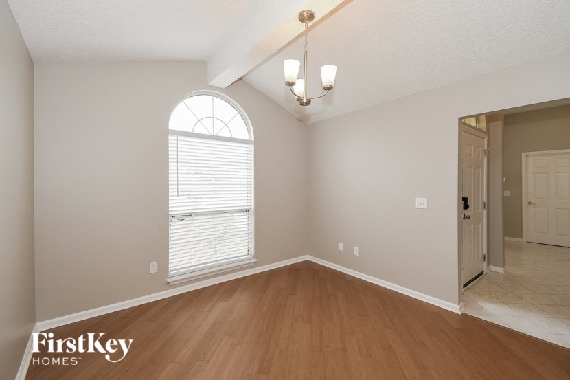 the spacious dining room with hardwood flooring and an arched window