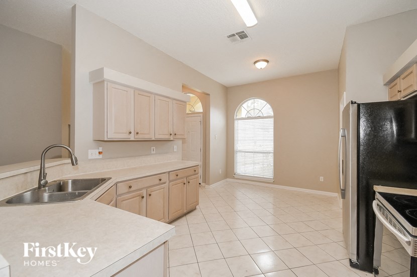 a kitchen with white counters and a sink and a refrigerator