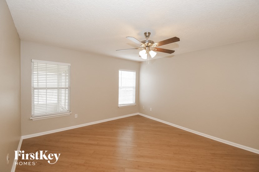 an empty living room with a ceiling fan and wood floors