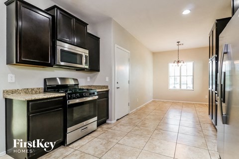 A kitchen with black cabinets and a granite countertop.