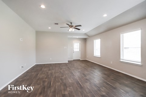 A spacious room with wooden flooring and a ceiling fan.