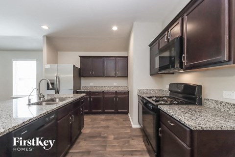 A kitchen with dark brown cabinets and granite countertops.