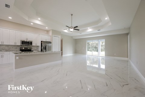 an empty kitchen and living room with a ceiling fan