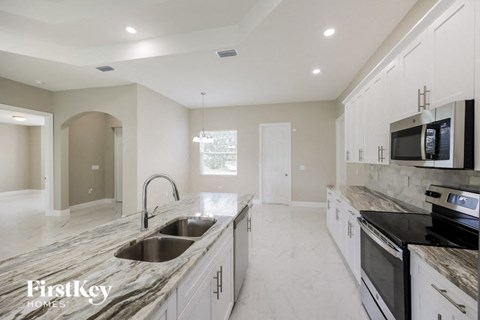a large kitchen with marble counter tops and white cabinets