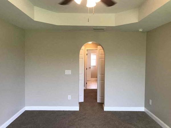 A room with a carpeted floor and a ceiling fan.