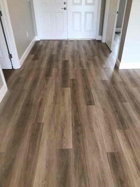 A hallway with a white door and brown wood flooring.