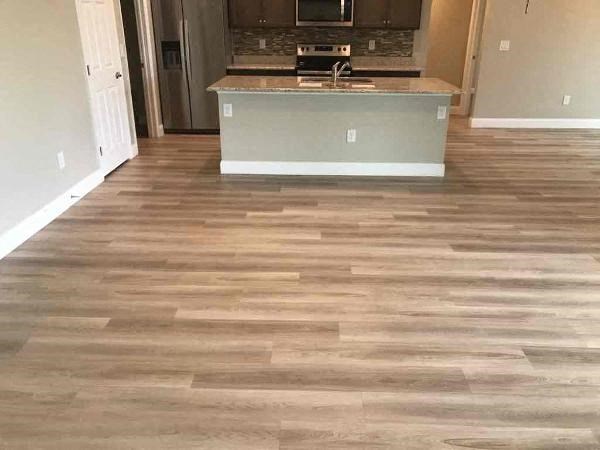 A kitchen island with a sink is in the middle of a room with wood flooring.