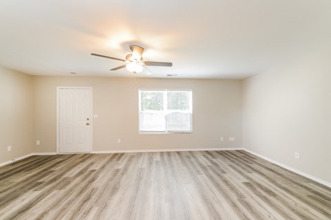 an empty living room with a ceiling fan and a window