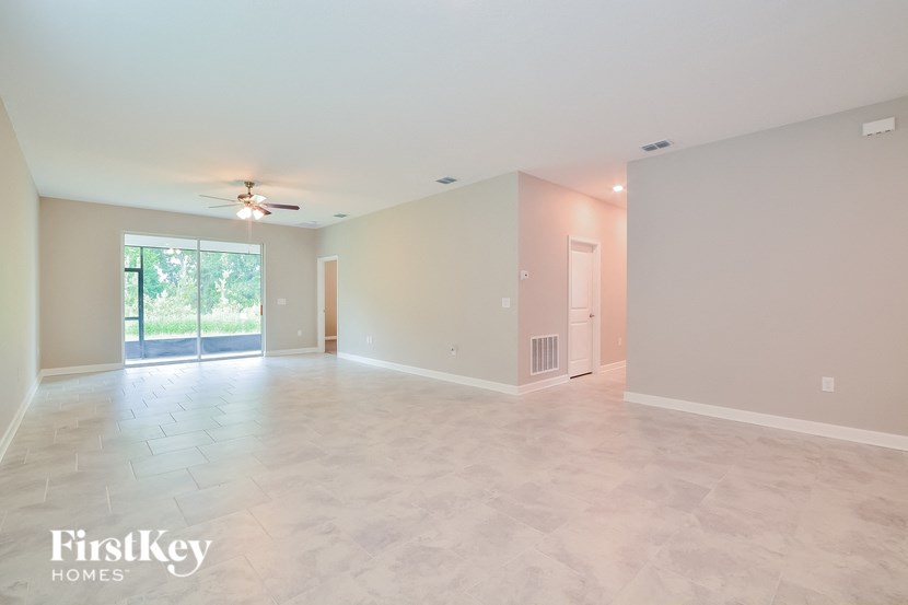 A spacious empty room with a sliding glass door leading to a garden.