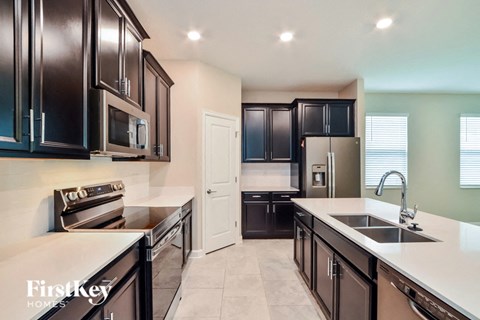 A kitchen with dark cabinets and a white countertop.