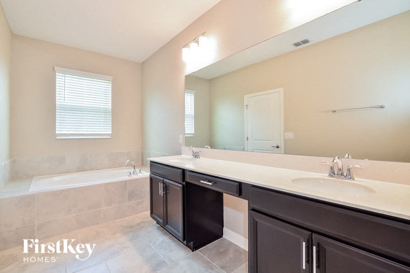 A bathroom with a tub, sink, and mirror.