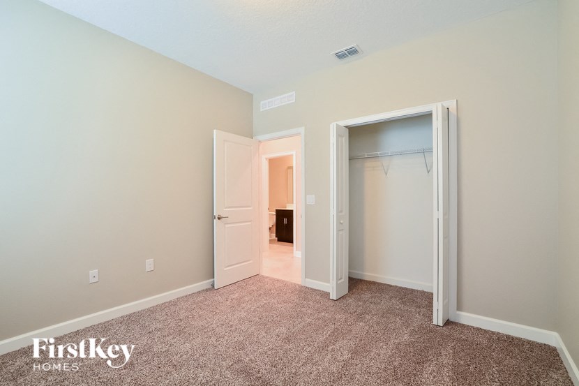 A room with a carpeted floor and a closet with a door open.