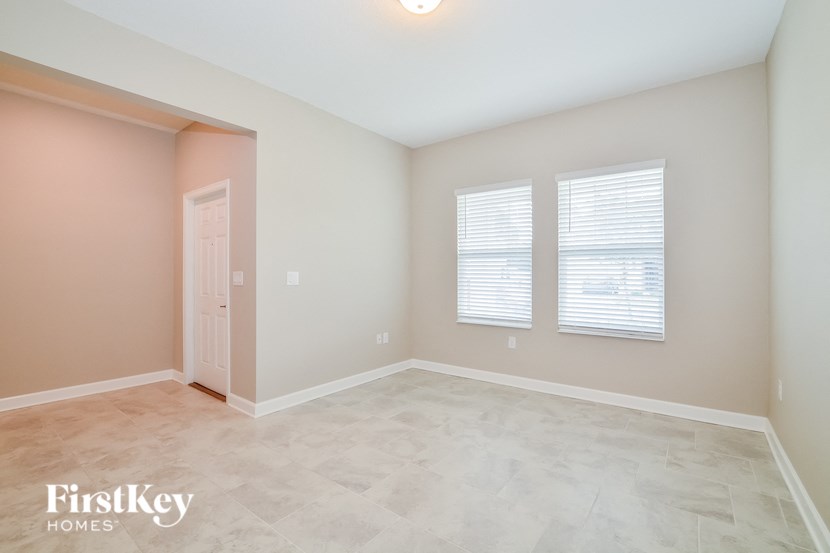 A room with a door, two windows with blinds, and a light on the ceiling.