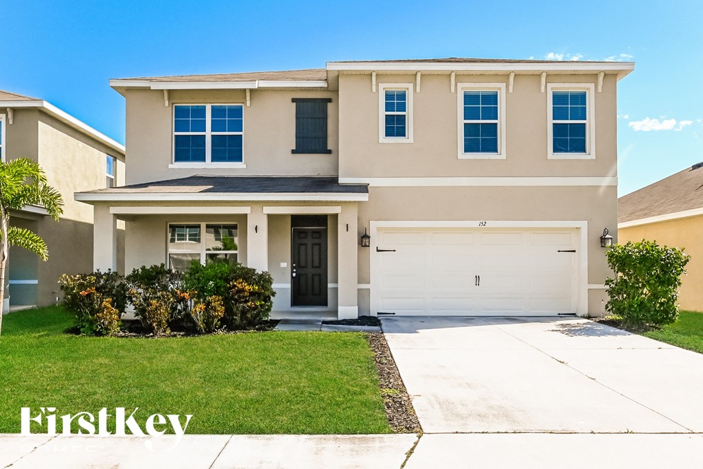 a beige house with a garage door and a lawn