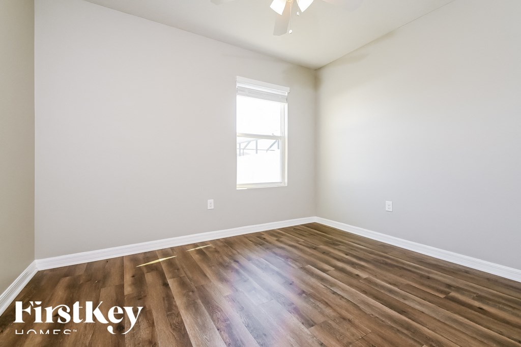 the second bedroom with hardwood flooring and a window